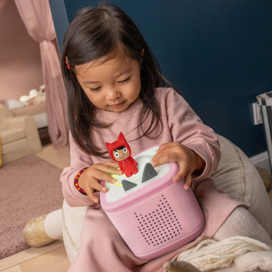 Child playing with a pink toy in a room setting