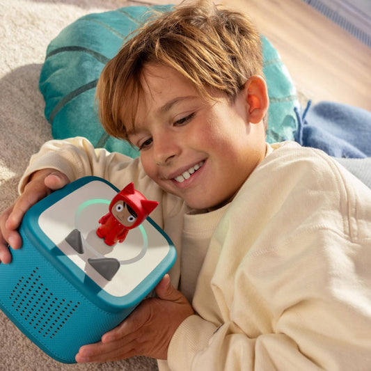 Child holding a blue toy device with a red character on a light surface