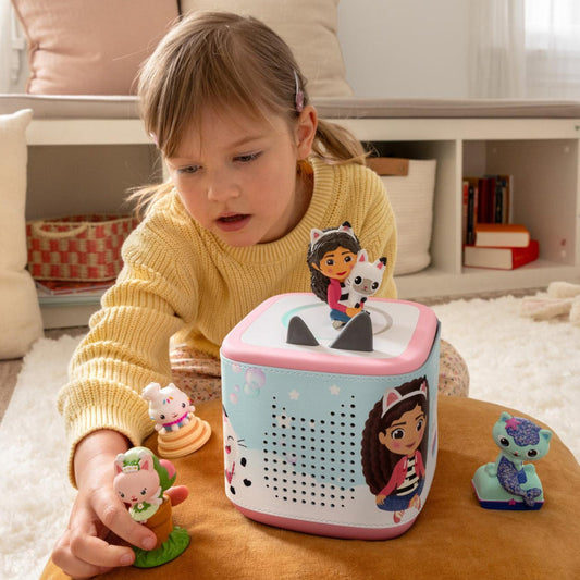 Child playing with a toy box featuring cartoon characters in a cozy living room.