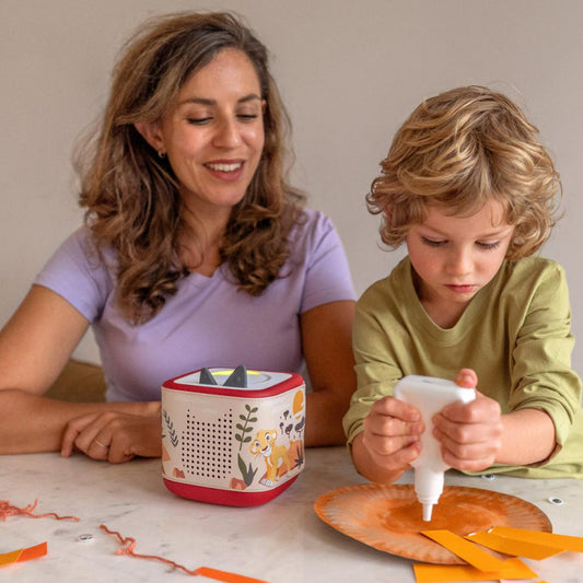 Woman and child at a table with craft materials, smiling.