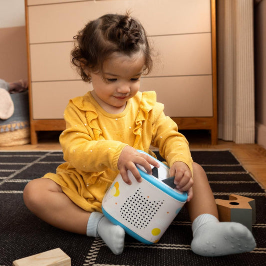 Child playing with a toy robot on a rug in a room.
