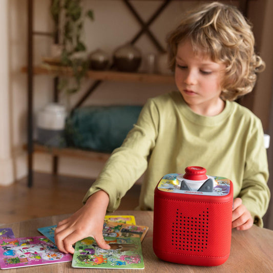Child playing with a red toy device on a table