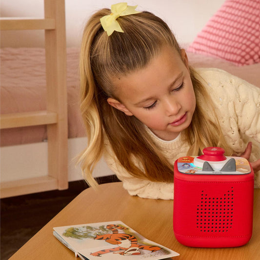 Young girl interacting with a red toy device on a table