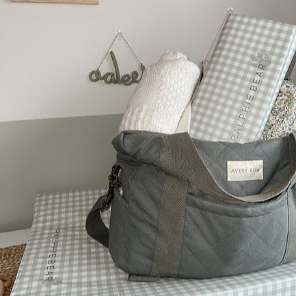 Gray bag with checkered blanket and Ralph Lauren towel on a bed
