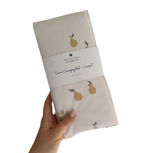 Packaged travel changing mat with pear design held by a hand on a white background