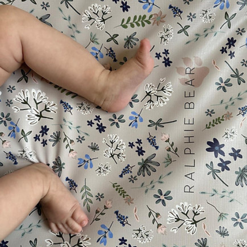Baby legs on a floral-patterned fabric with 'Ralphie Bear' branding.