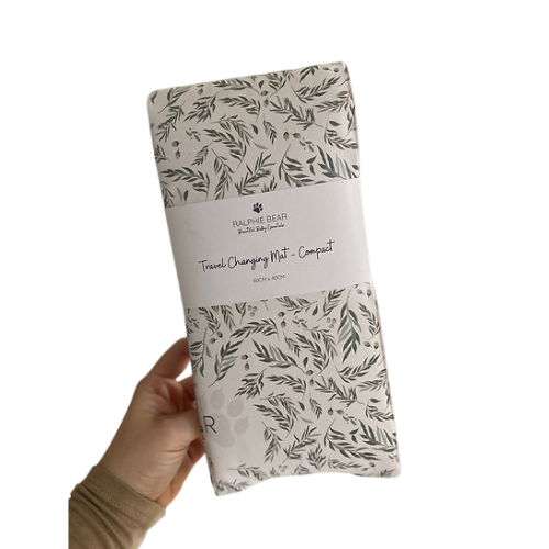 Packaged travel changing mat with leaf pattern held by a hand on a white background