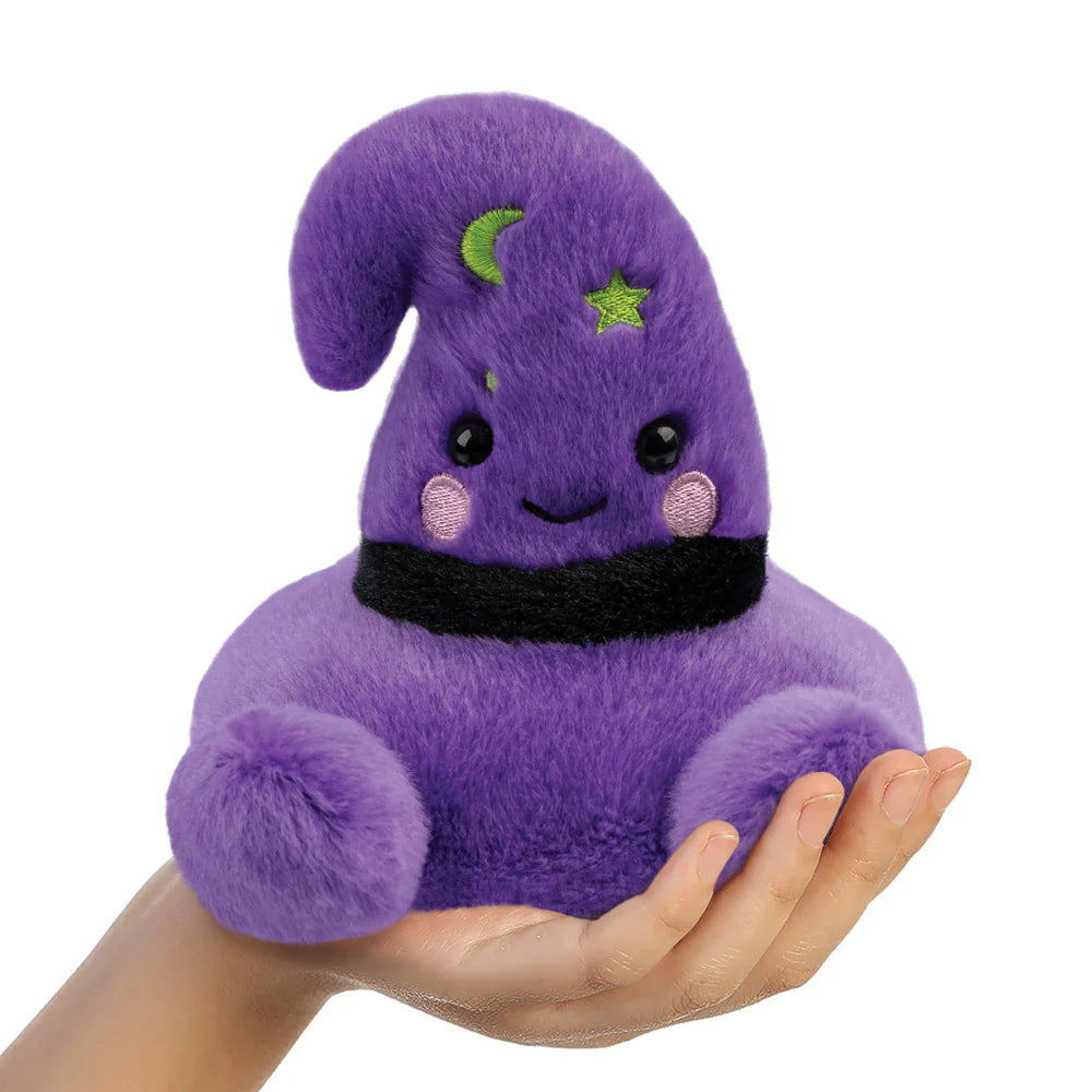 Purple plush toy with a black belt held in a hand on a white background