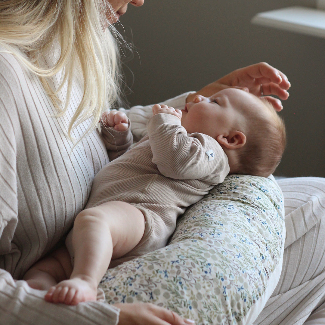 Woman holding a baby on a floral-patterned cushion