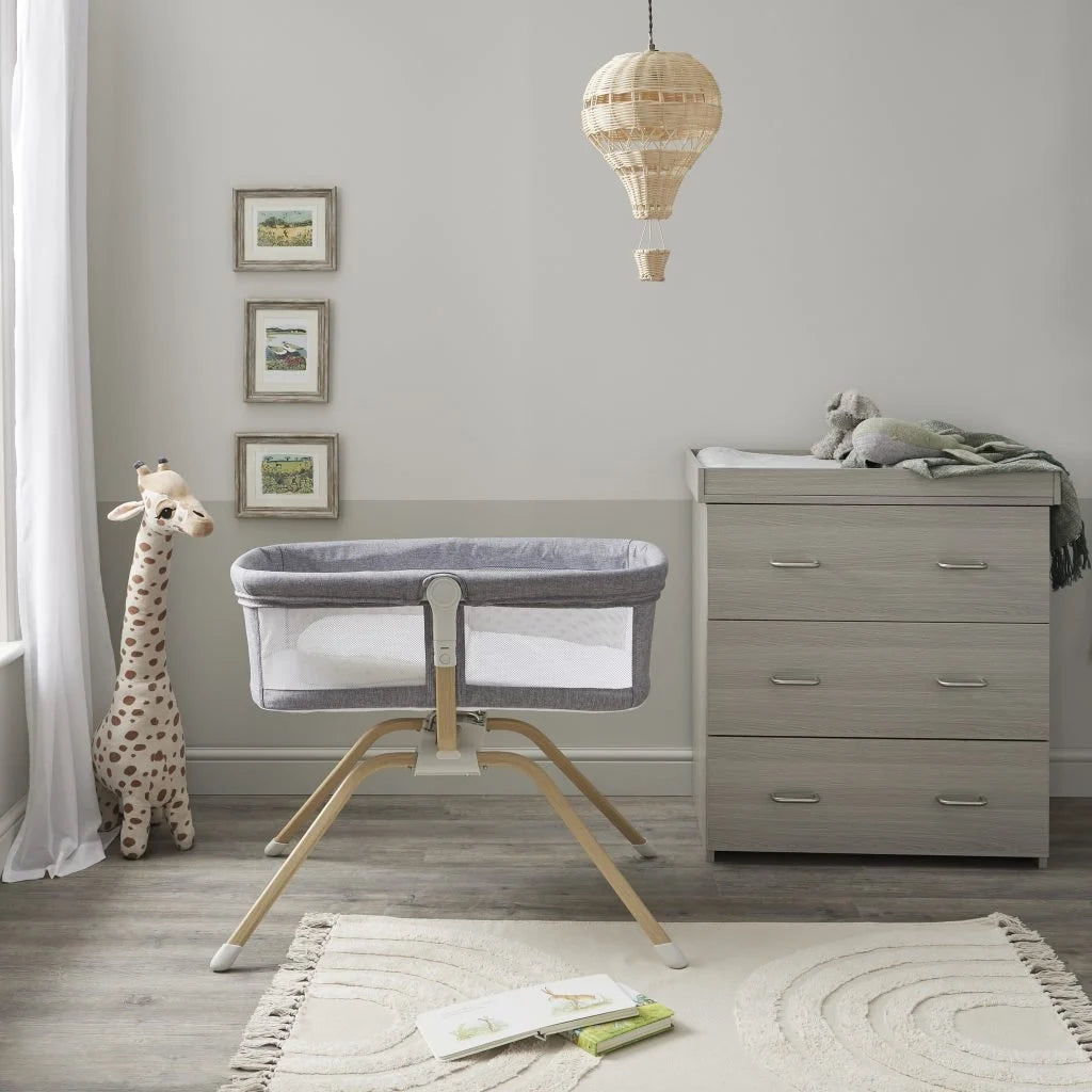 Nursery room with a crib, dresser, and toys on a wooden floor.