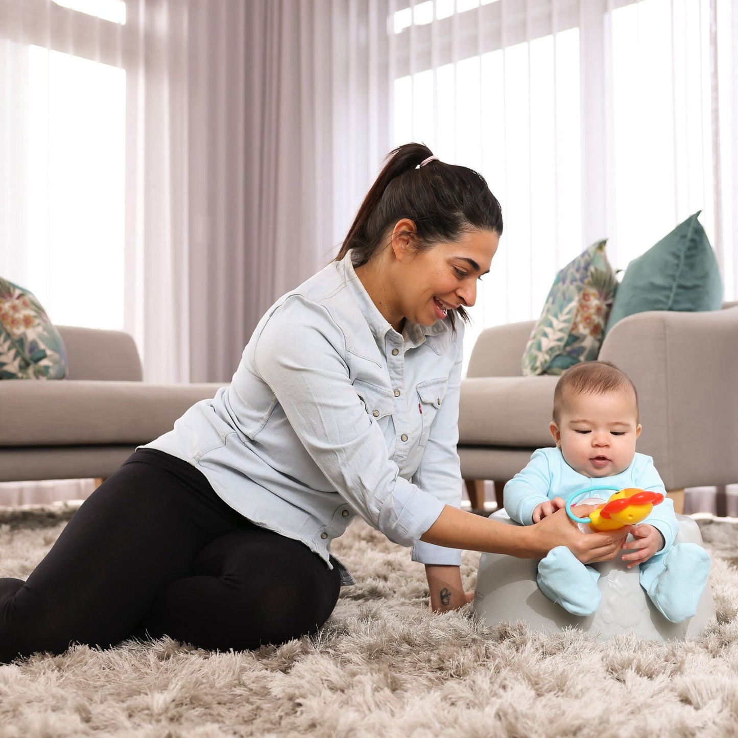 Woman playing with a baby on a carpeted floor in a living room.
