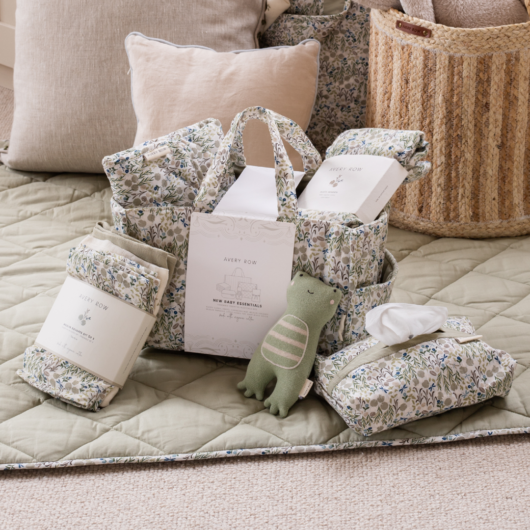 Baby care products including pillows, a blanket, a plush toy, and tissues on a quilted surface.