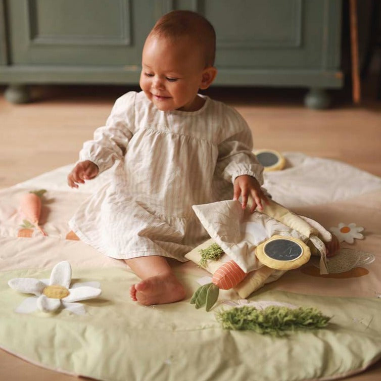 Baby playing with a toy on a soft surface