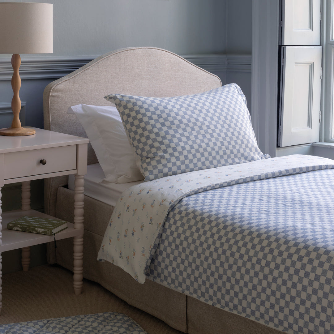 Bedroom with a bed featuring checkered bedding, a lamp, and a nightstand.
