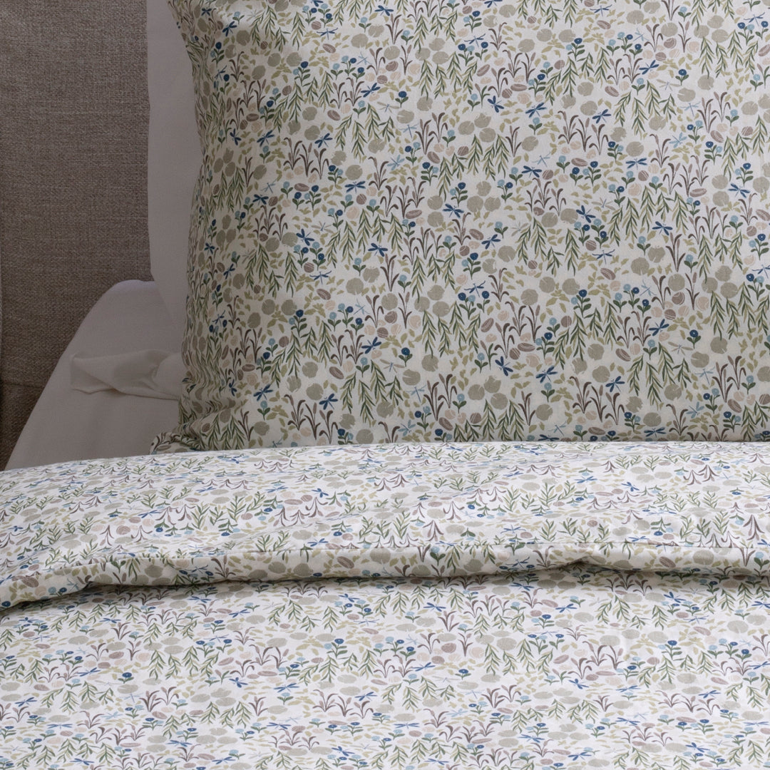 Floral patterned bedding set on a bed with a pillow in the background.