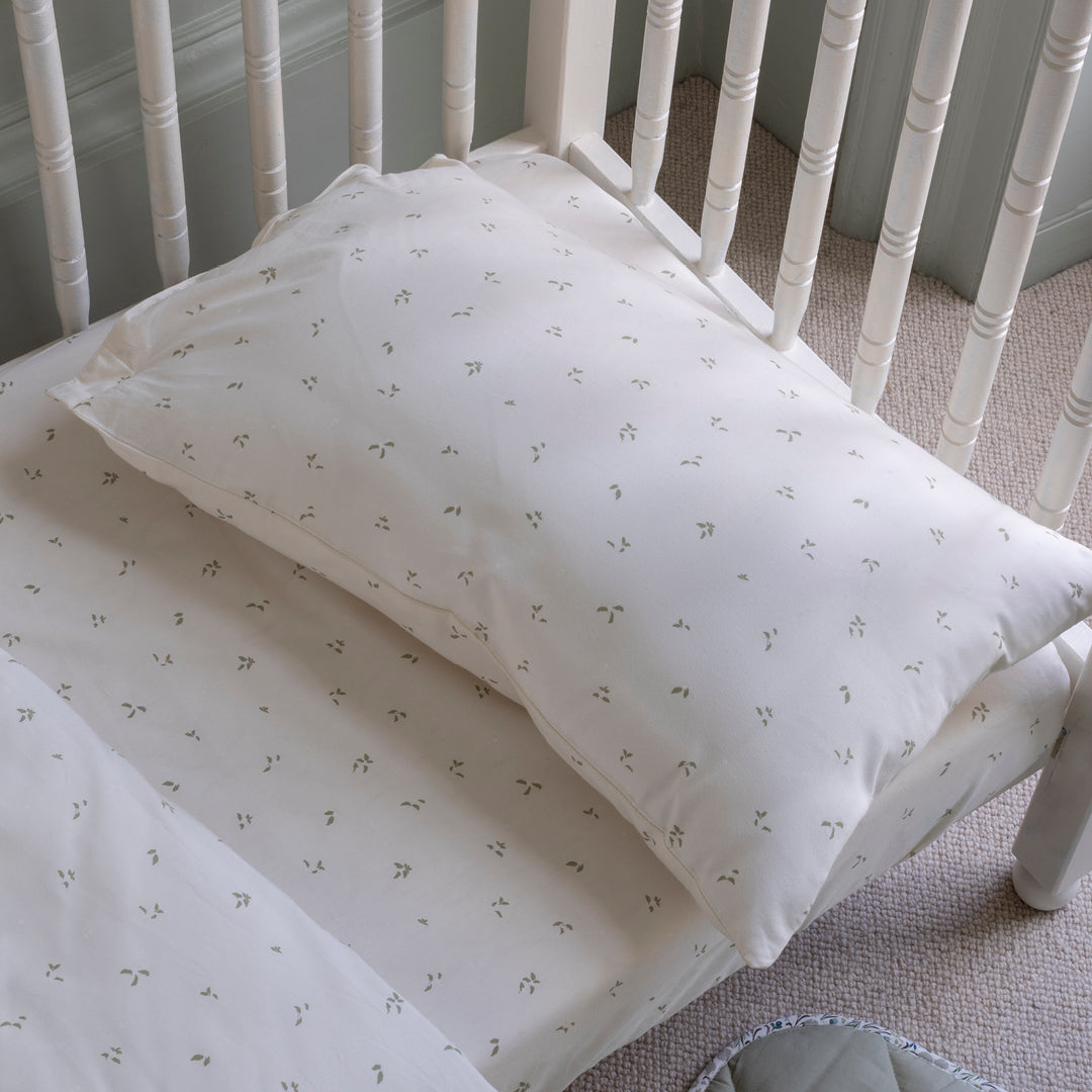 White crib with floral-patterned bedding and pillow