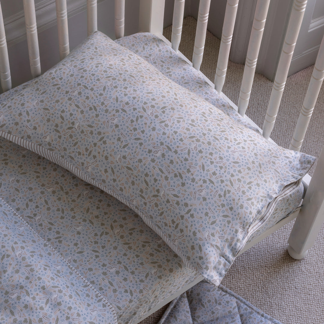 Floral-patterned pillow and blanket on a white crib