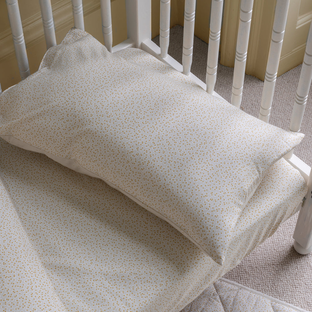Crib with a white pillow and fitted sheet in a nursery setting