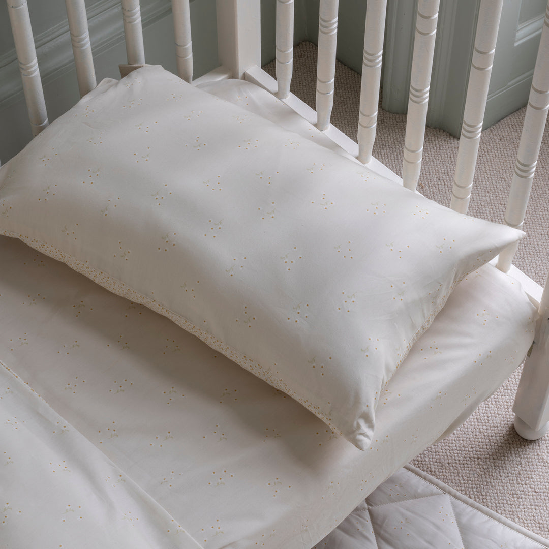 White pillow on a white crib with a neutral background