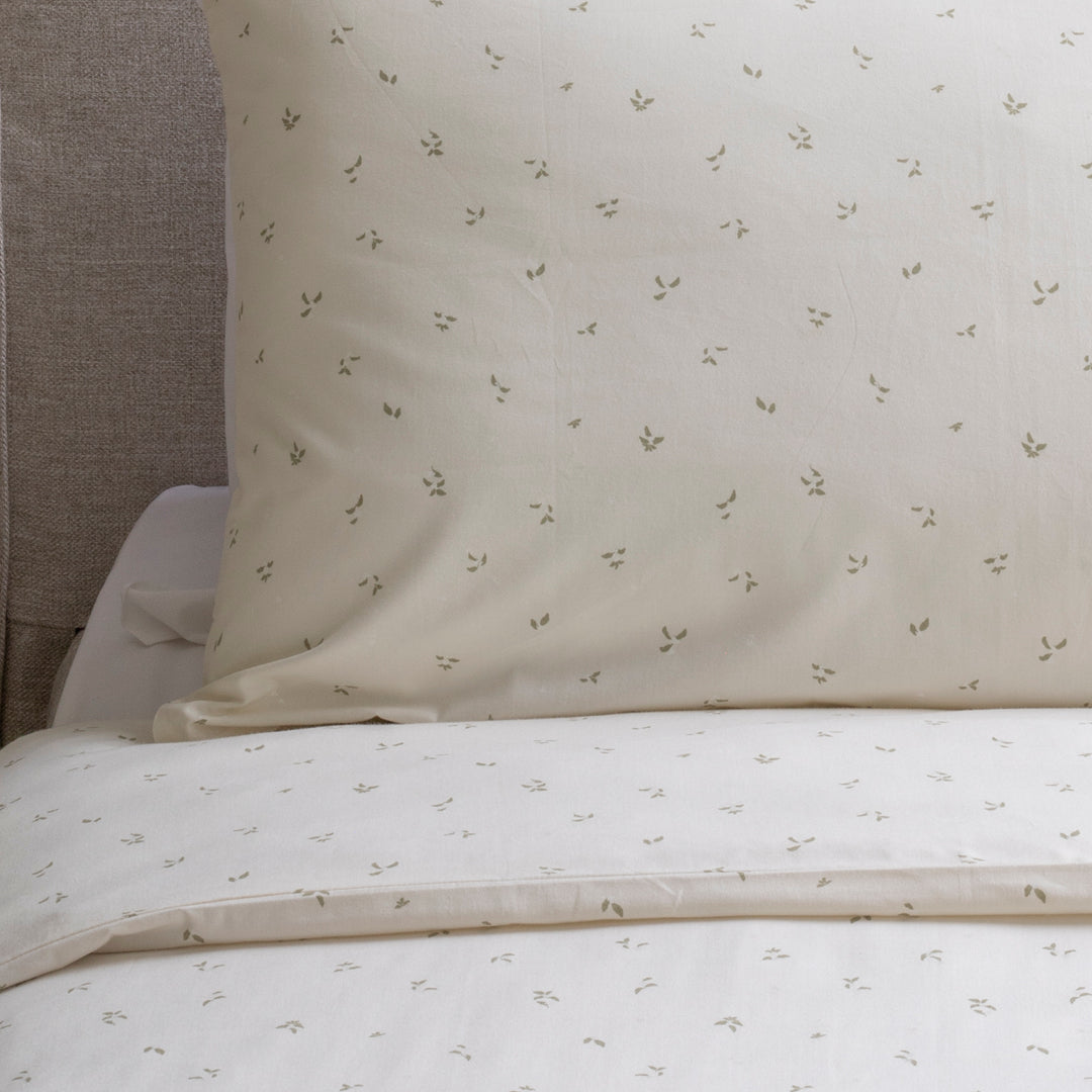 Bedding set with floral pattern on a bed against a neutral wall.