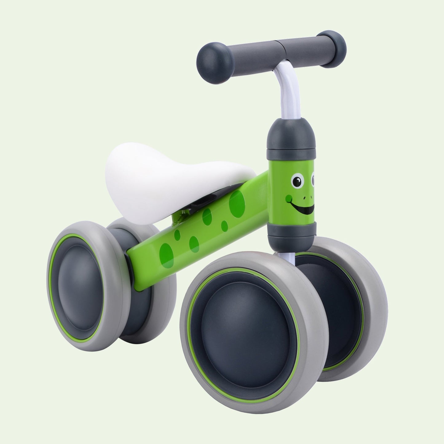 Children's balance bike with green frame and gray wheels on a light green background
