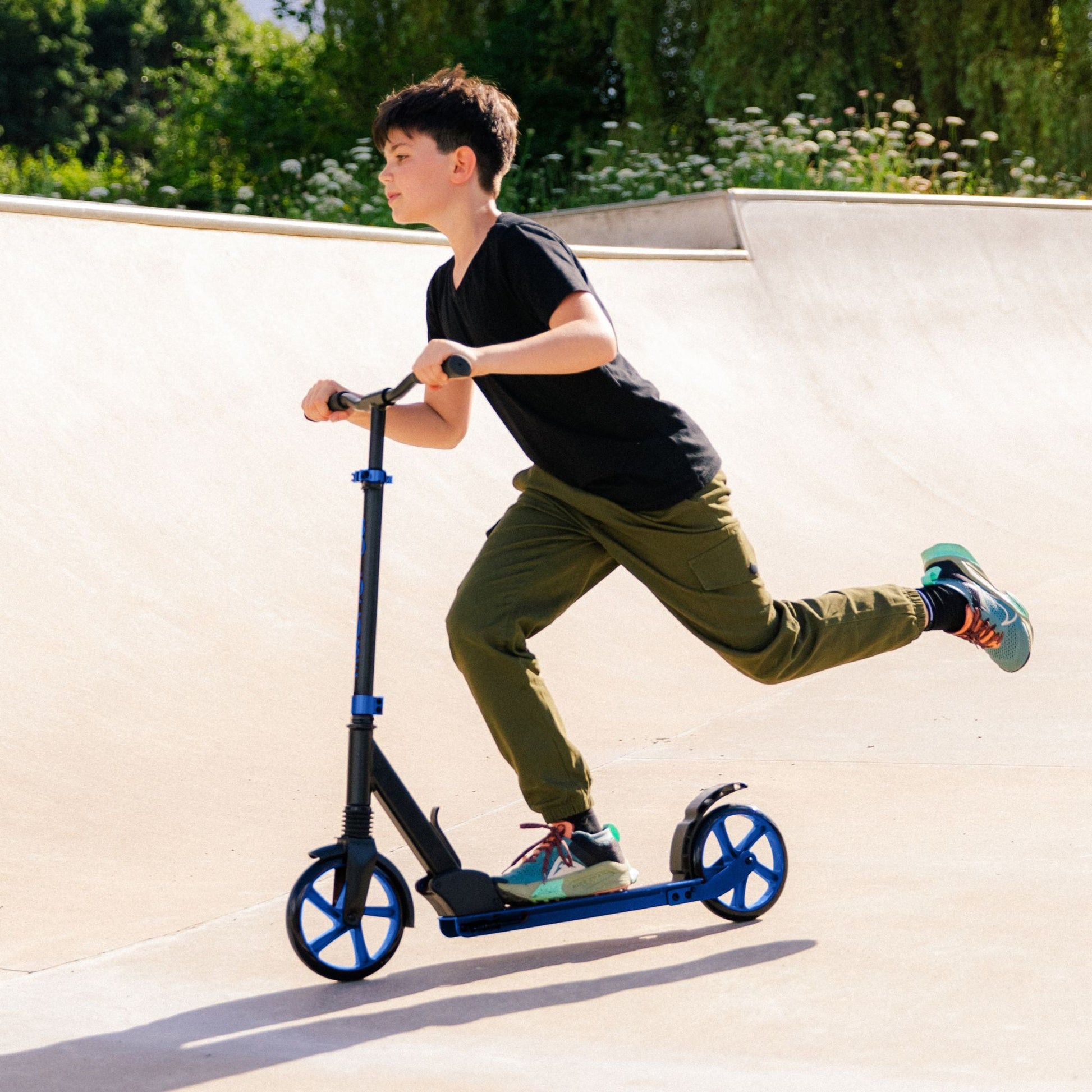 Person riding a scooter on a concrete surface with greenery in the background
