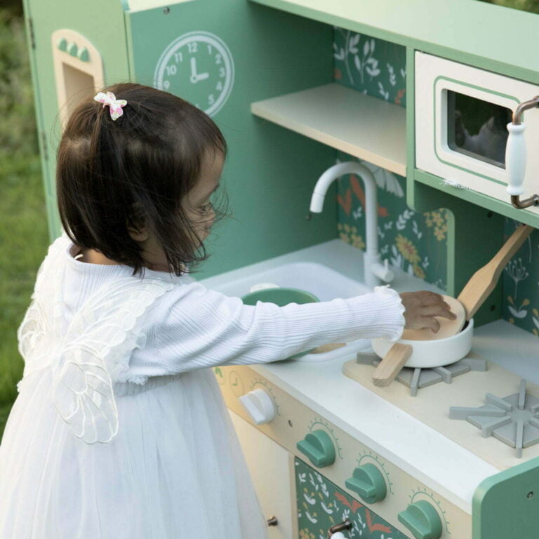 Child playing with a wooden play kitchen set outdoors