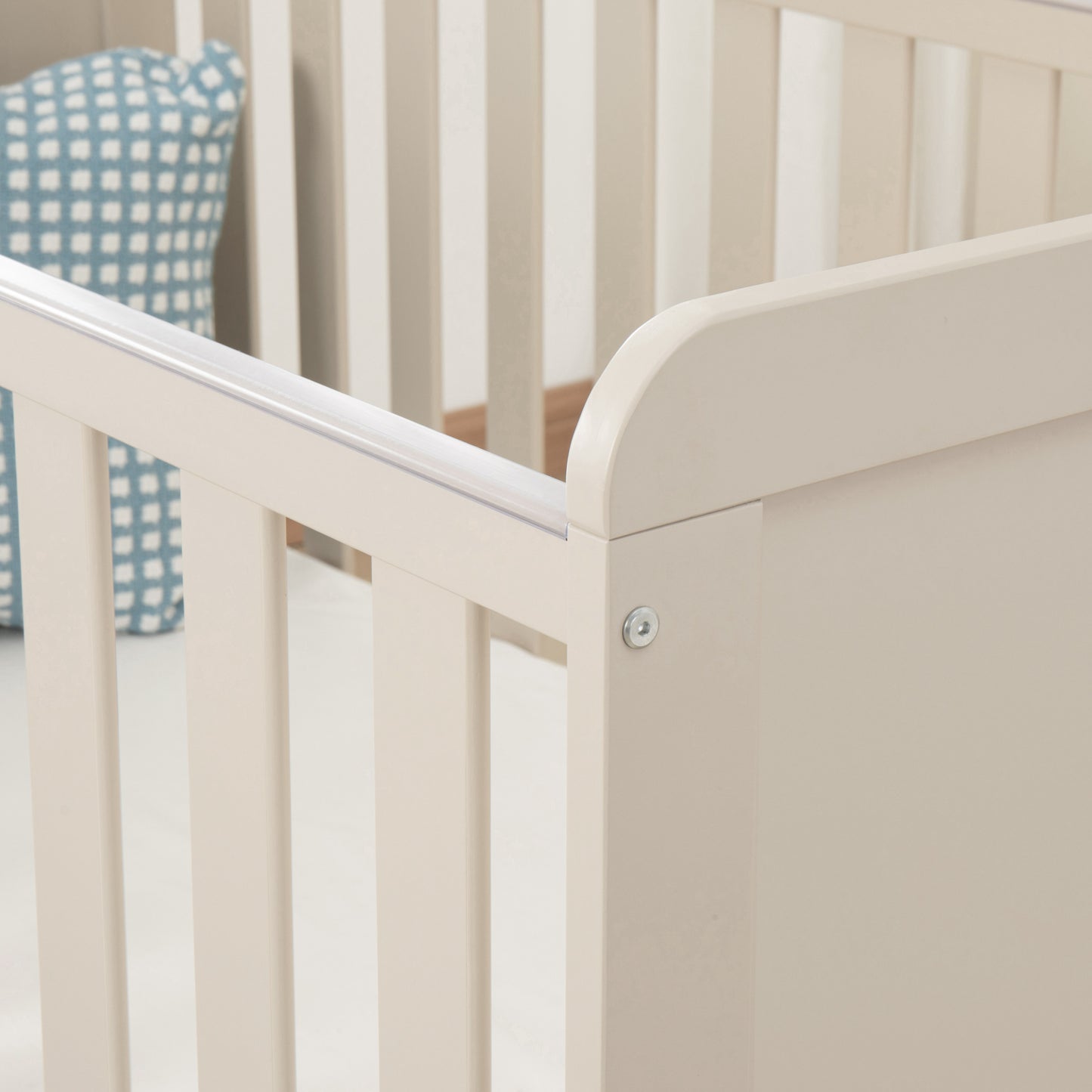 Cashmere Cot with a blue and white checkered pillow in the corner