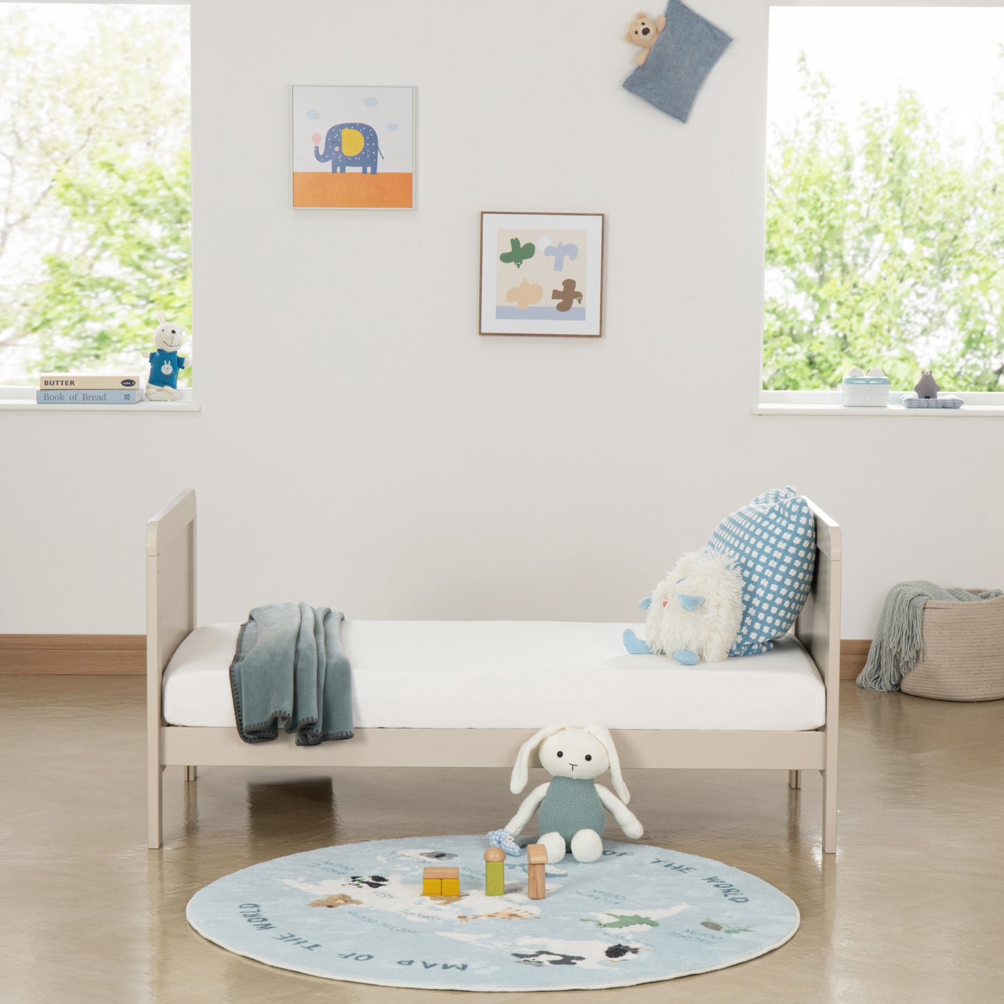 Children's room with a toddler bed, toys, and a rug on a wooden floor.