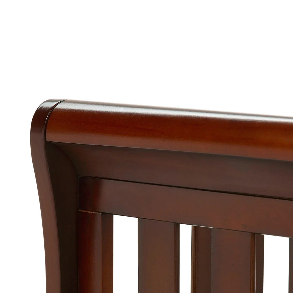 Close-up of a wooden crib with a dark brown finish on a white background