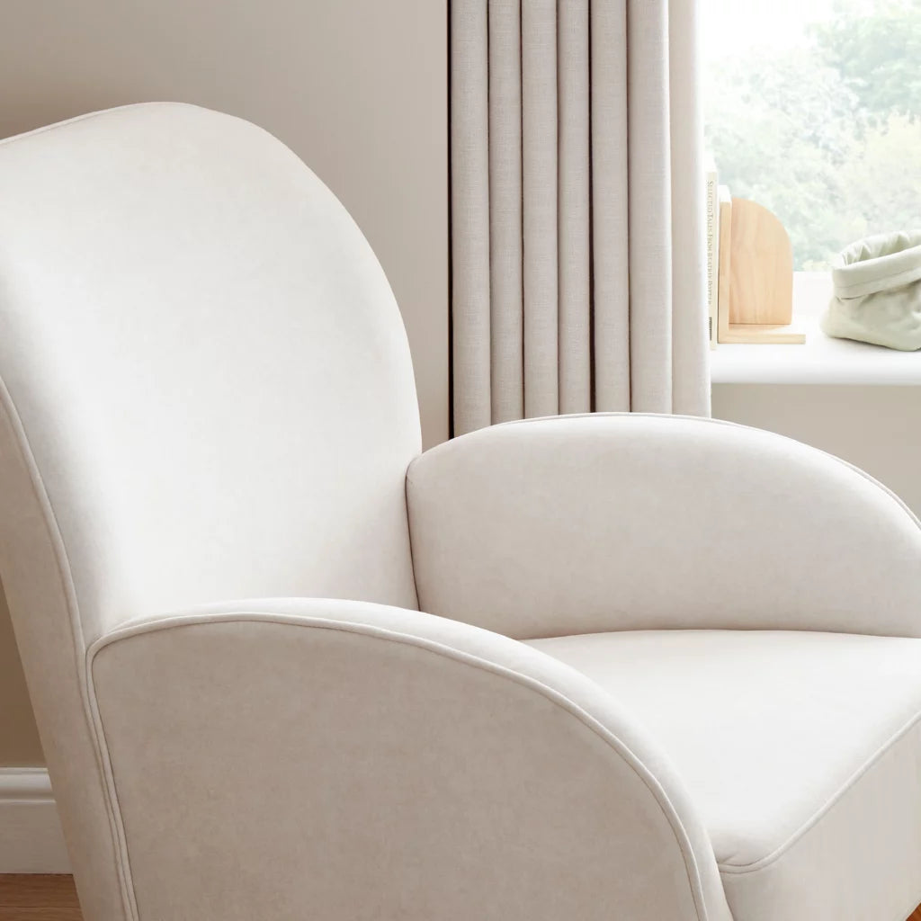 White armchair in a room with light-colored walls and a window.