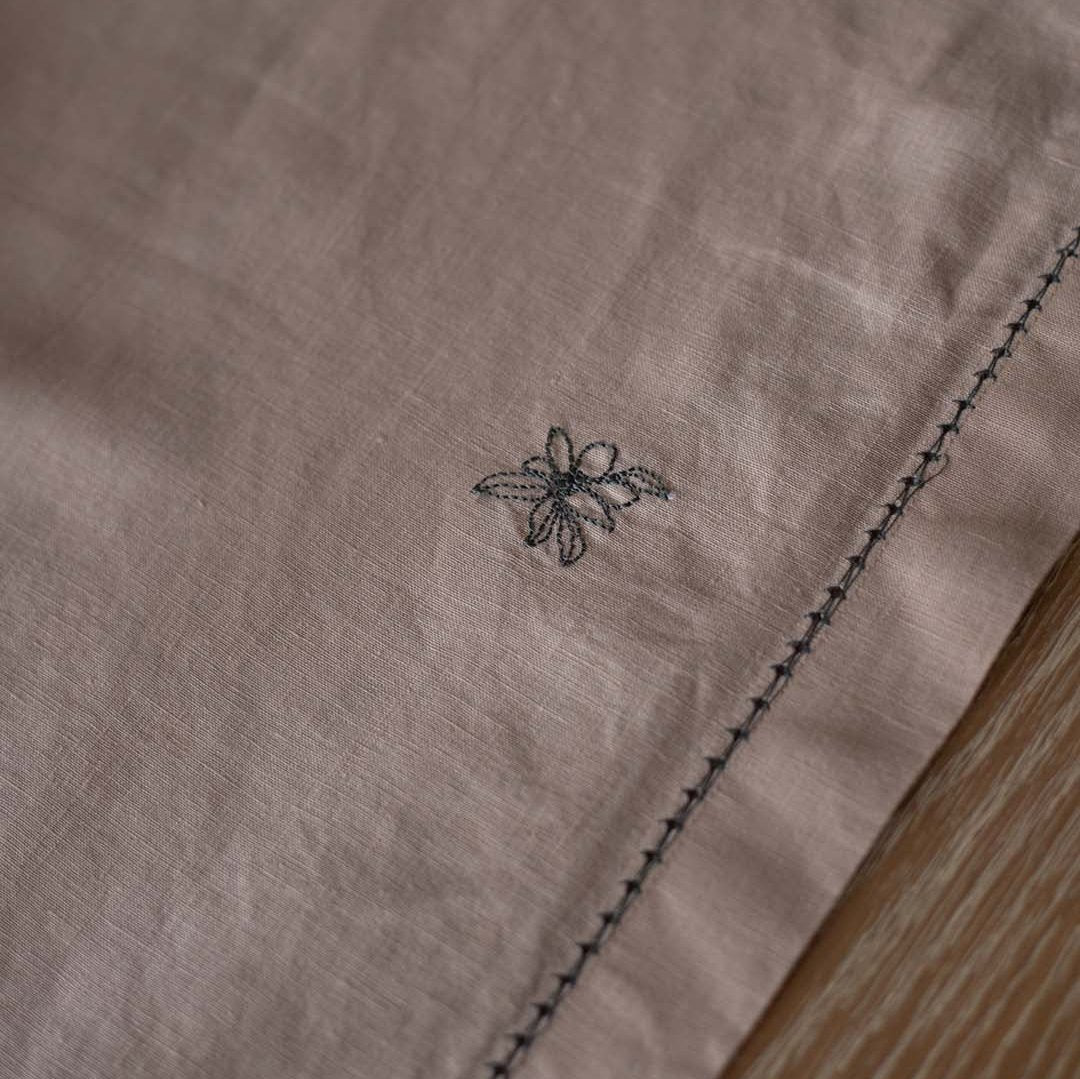 Close-up of a brown fabric with a small embroidered design on a wooden surface