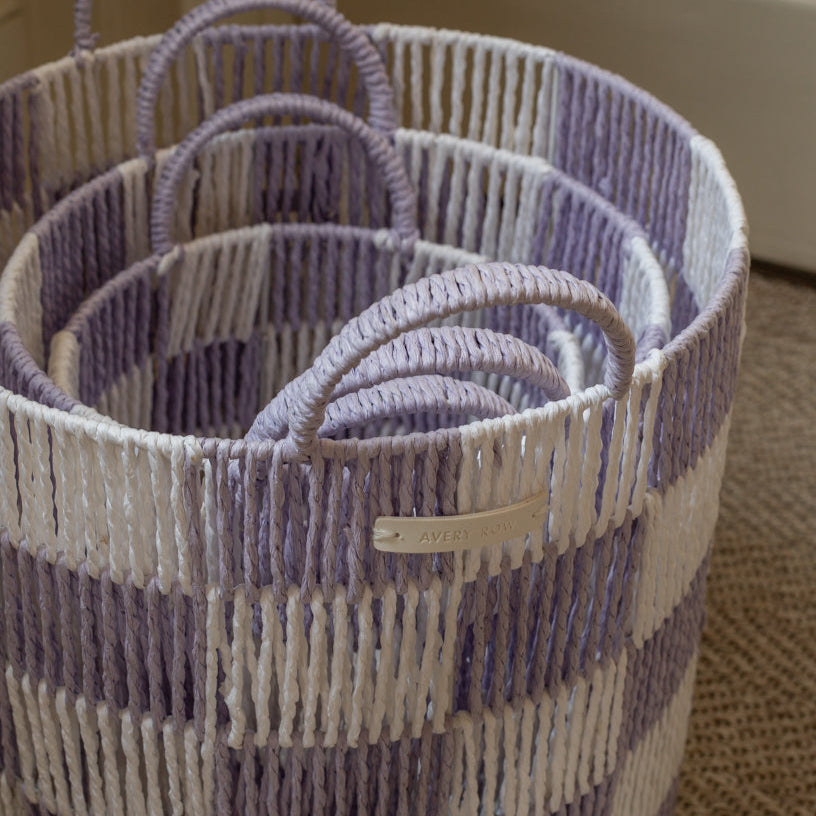 Woven baskets with handles in purple and beige on a neutral background