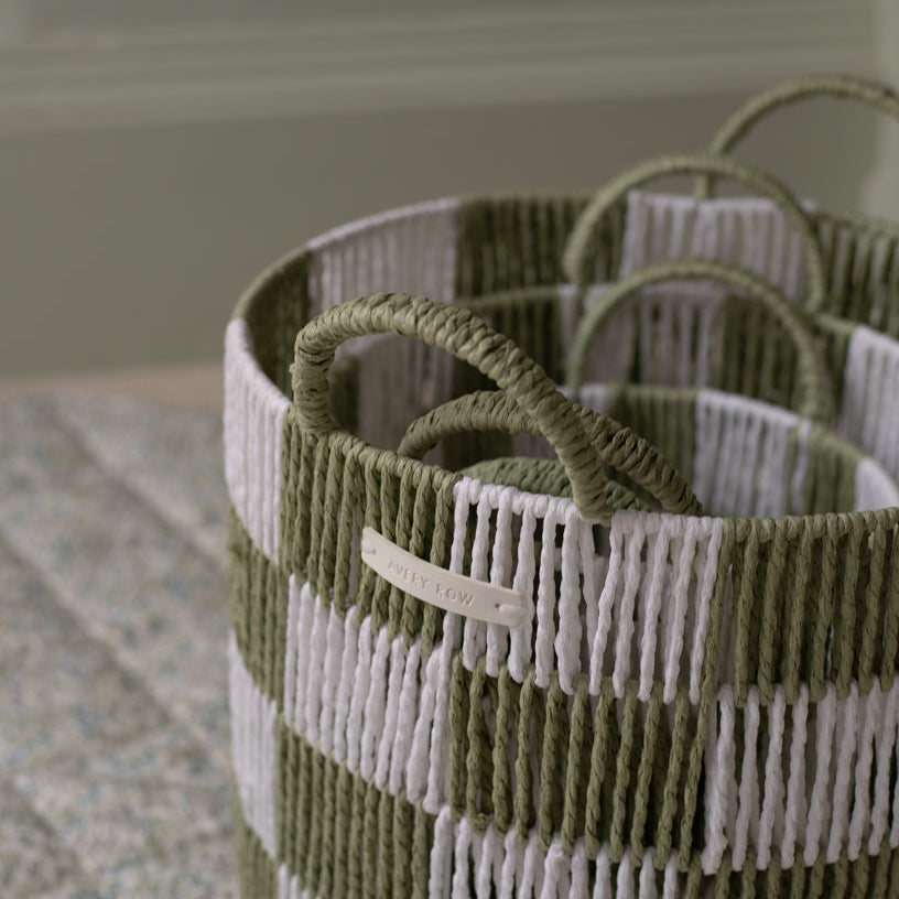 Green and white striped basket with handles on a neutral background