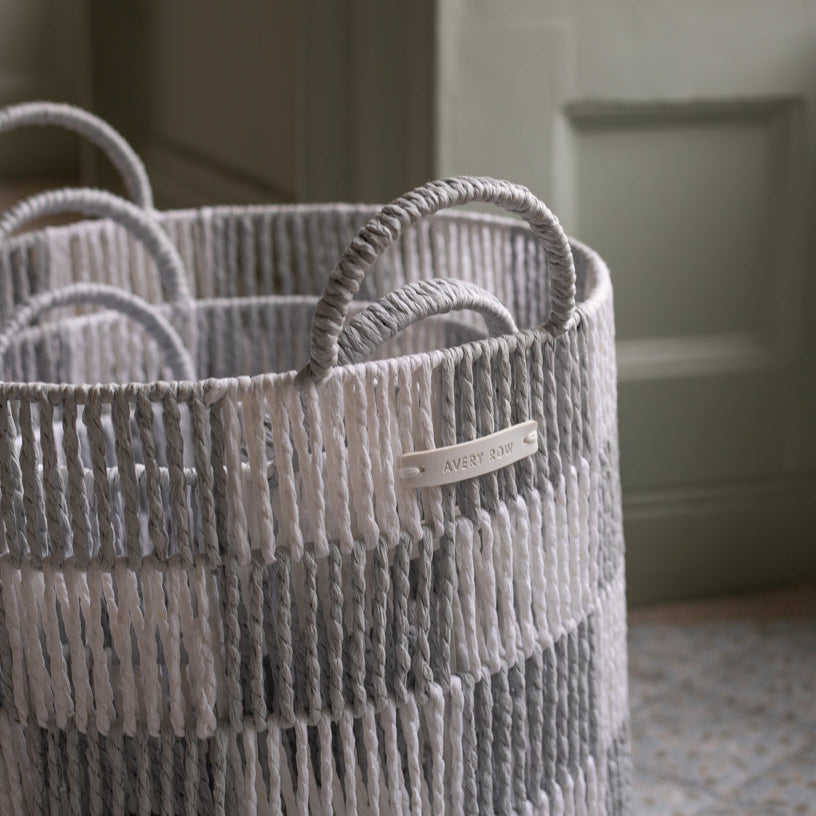 Woven basket with handles and a visible brand label on a neutral background