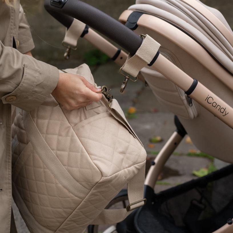 Person adjusting a beige quilted bag attached to an iCandy stroller.
