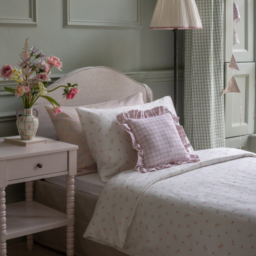 Bedroom with floral arrangement on nightstand and checkered curtain