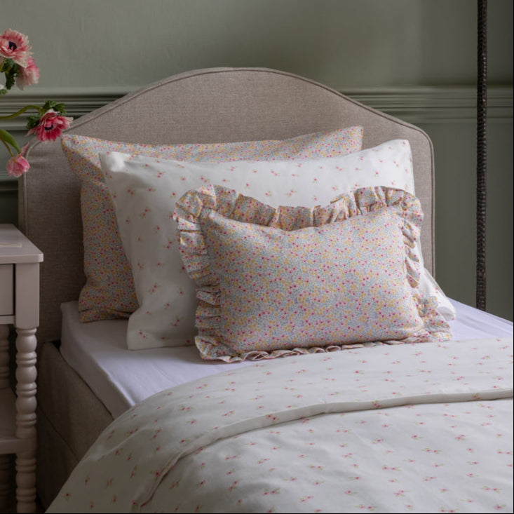 Bed with floral-patterned pillows and bedding in a bedroom setting.