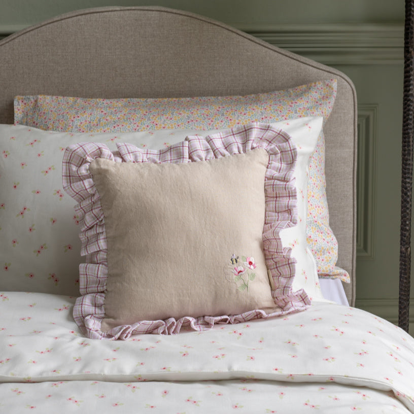 Decorative pillows with ruffled edges on a bed with floral bedding.