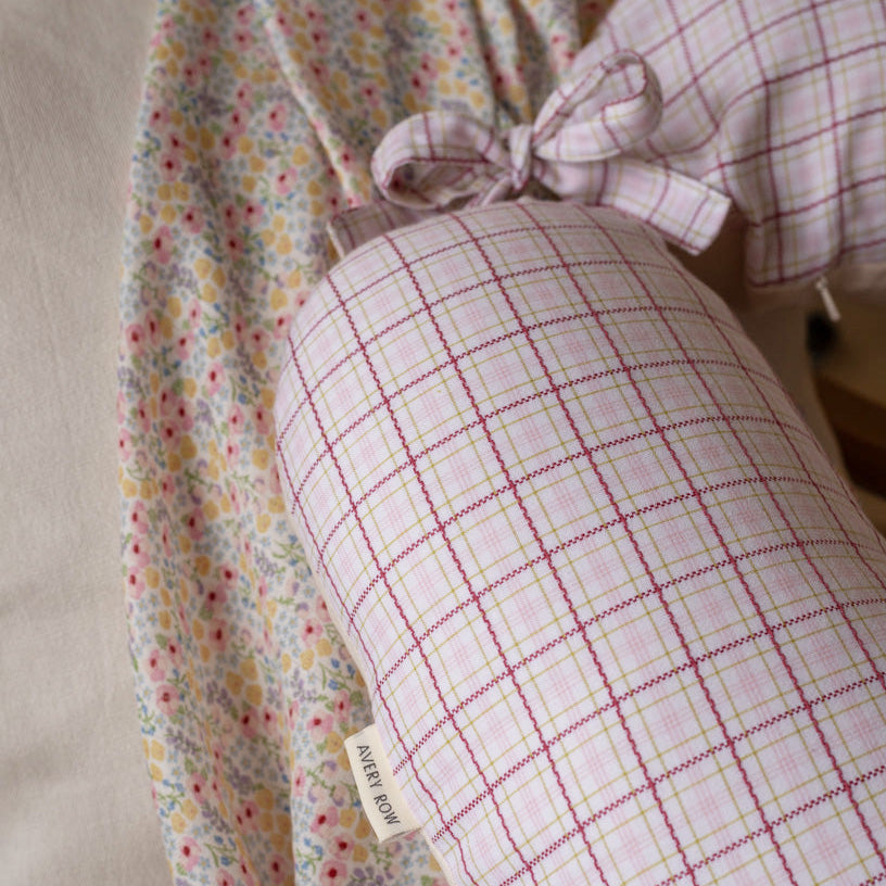 Pink checkered pillow with a bow on a floral fabric background