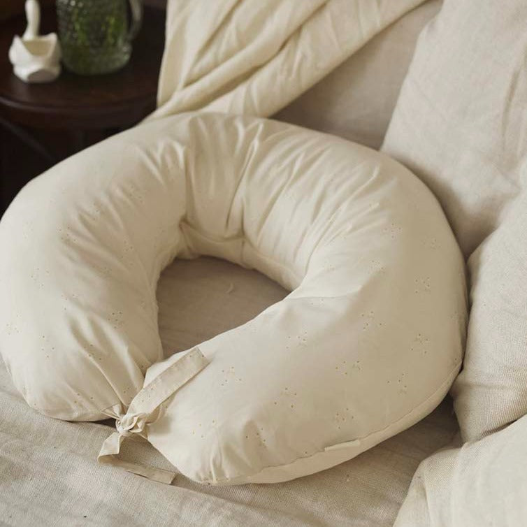 Beige U-shaped pillow on a bed with beige bedding