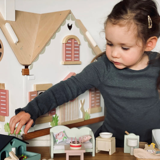 Child playing with a toy dollhouse and furniture
