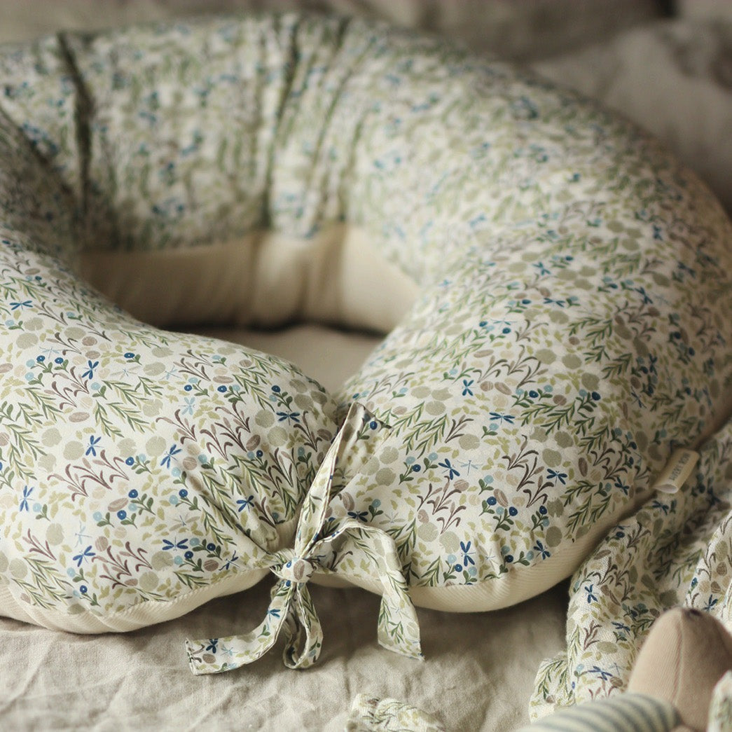 Floral-patterned nursing pillow on a bed