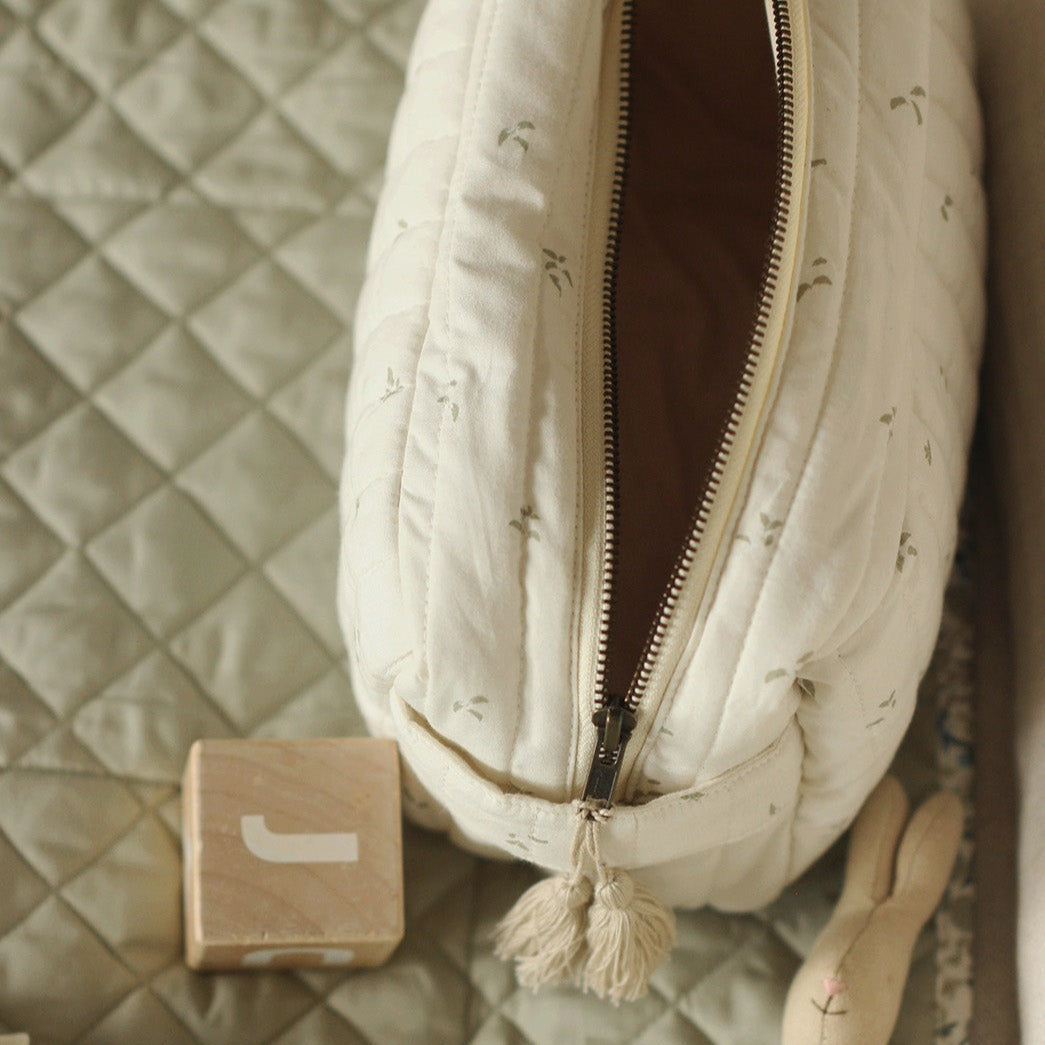 Beige quilted bag with zipper on a textured surface