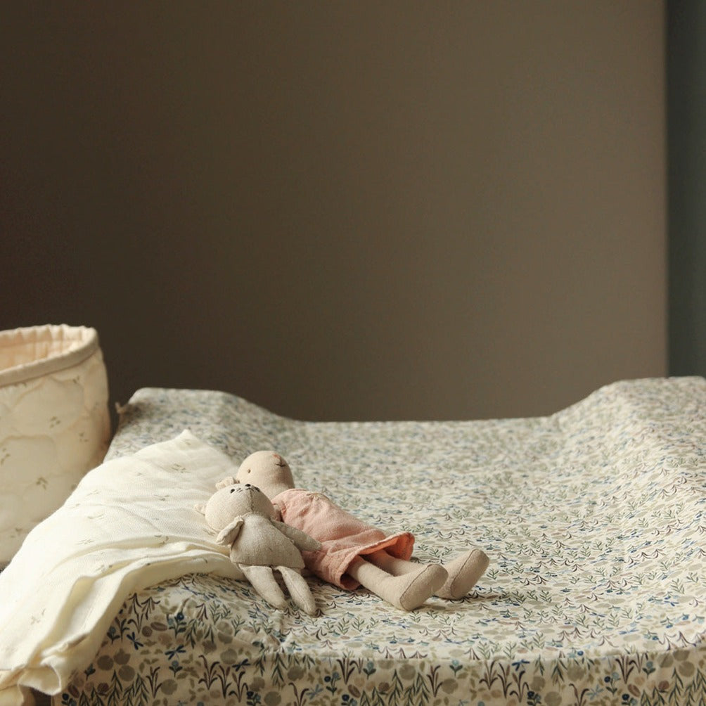Two stuffed animals on a floral-patterned surface with a plain background