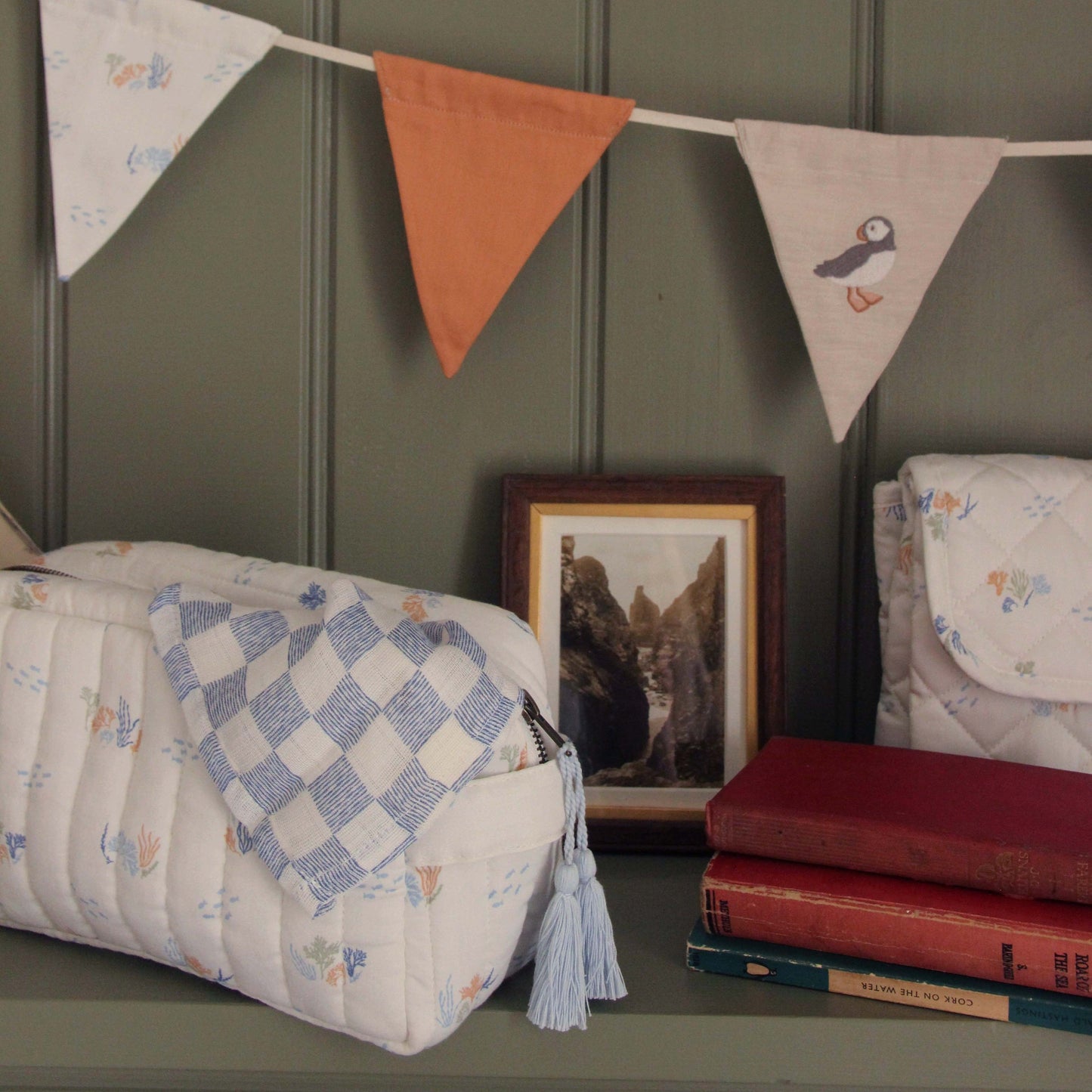 Decorative items including a quilt, books, and a framed picture on a shelf with a banner above.