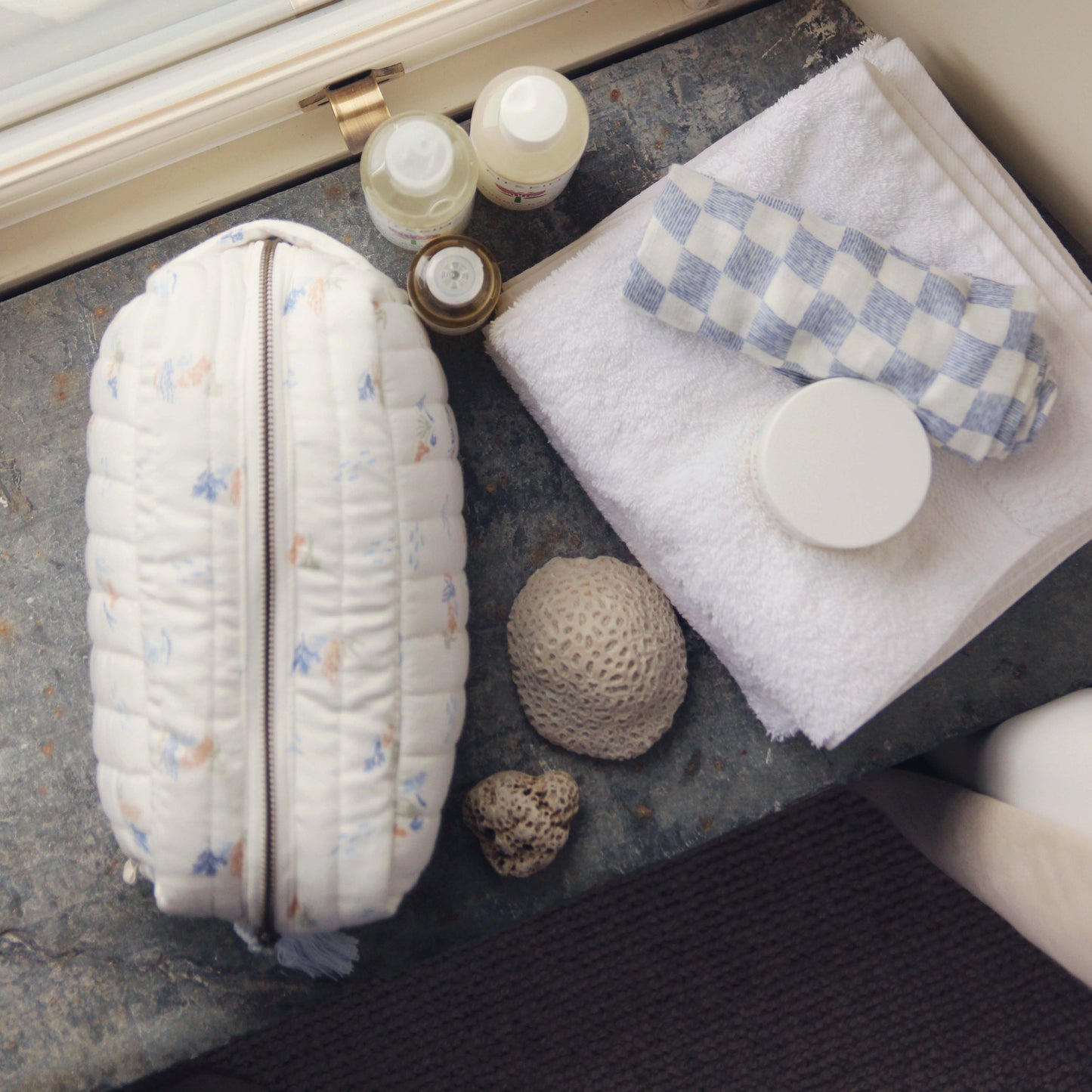 Cosmetic bag with toiletries on a textured surface