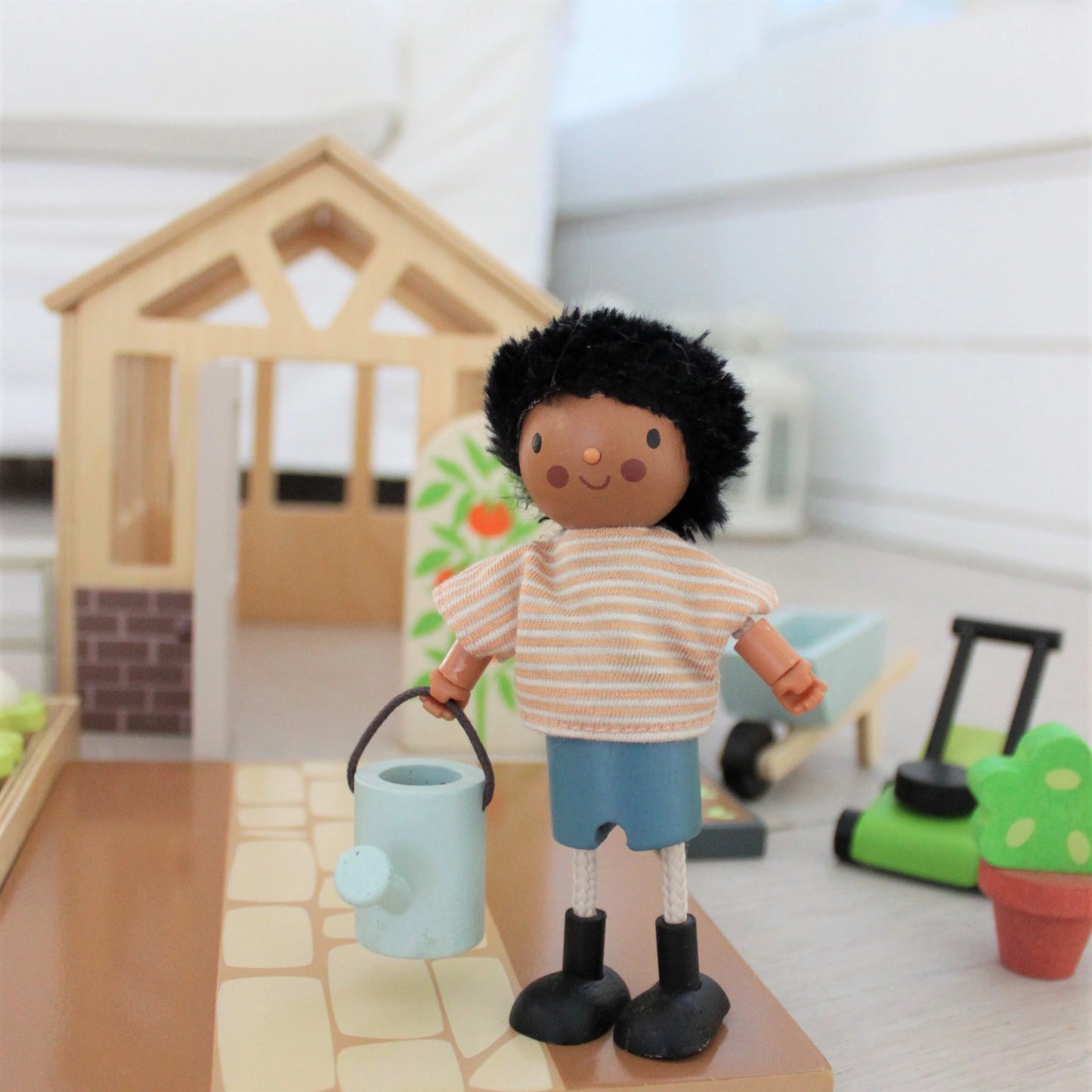 Toy figure of a child holding a watering can in a miniature garden setting