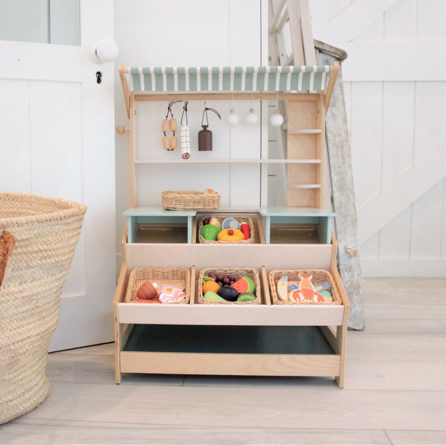 Children's play area with a wooden shelf unit and toys on a light wooden floor.