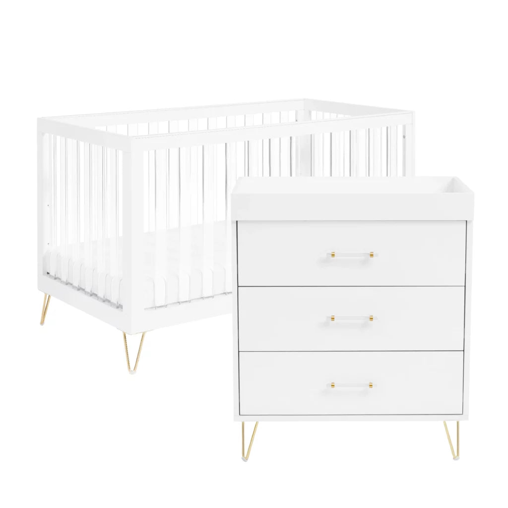 White crib and dresser set with gold legs on a white background